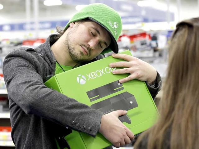 A man from Chicago, hugs his newest XBox One, costing $500, after he purchased it. (AP Photo)