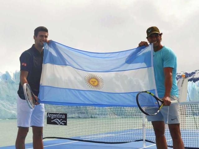 Novak Djokovic of Serbia and Rafael Nadal (R) of Spain pose biting an Argentinian national flag during an exhibition tennis match on a court set up on the deck of the "Argentino Supply" cargo ship, as the Perito Moreno glacier is seen in the background, near the Patagonian city of El Calafate. Djokovic and Nadal are in Argentina to attend a farewell event on Sunday for Argentina's David Nalbandian, who is retiring from professional tennis. (Reuters)