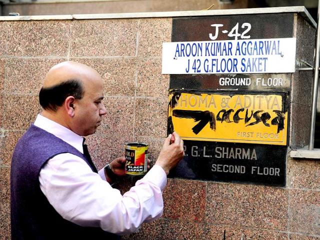 BJP leader Vijay Jolly writes 'accused' on the nameplate at residence of former managing editor of Tehelka magazine, Shoma Chaudhury in New Delhi. (HT photo)