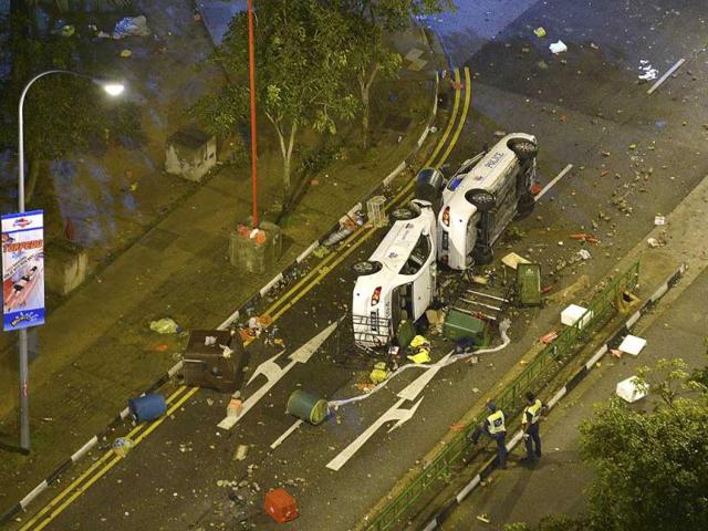 Police officers look at two overturned police cars along Race Course Road following a riot in Singapore's Little India district. (Reuters)