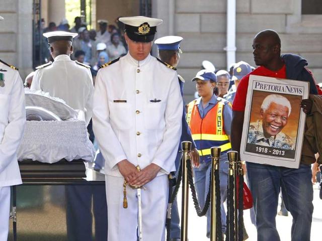 A man holds a portrait of South African former president Nelson Mandela as people bid farewell to Mandela as he lies in state at the Union Buildings in Pretoria. (AFP Photo)