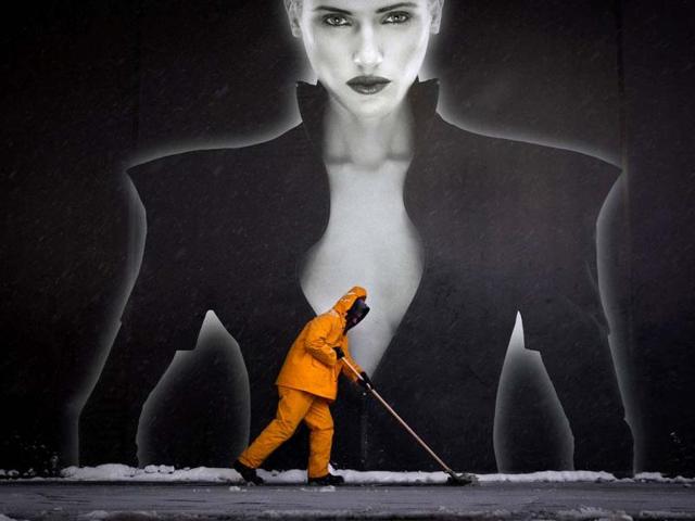 A worker clears wet snow off a sidewalk with a squeegee in front of a billboard sign in Times Square in New York. A major storm, called Hercules, hit the northeastern US bringing heavy snow and delaying or canceling thousands of flights. (Reuters photo)