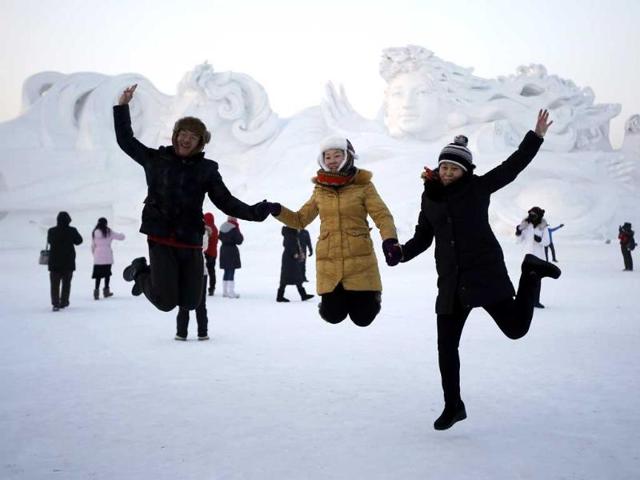 Visitors jump for a picture in front of a large snow sculpture at the Harbin International Snow Sculpture Art Expo in the northern city of Harbin, Heilongjiang province. (Reuters photo)
