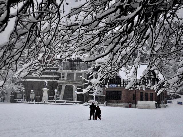 A couple walk down a snow covered road at Ridge in Shimla. (Santosh Rawat/HT Photo)