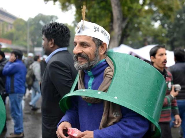 A supporter of New Delhi chief minister Arvind Kejriwal wears a trash bin top over his head on a rainy morning during a sit-in protest in New Delhi. (AFP Photo)