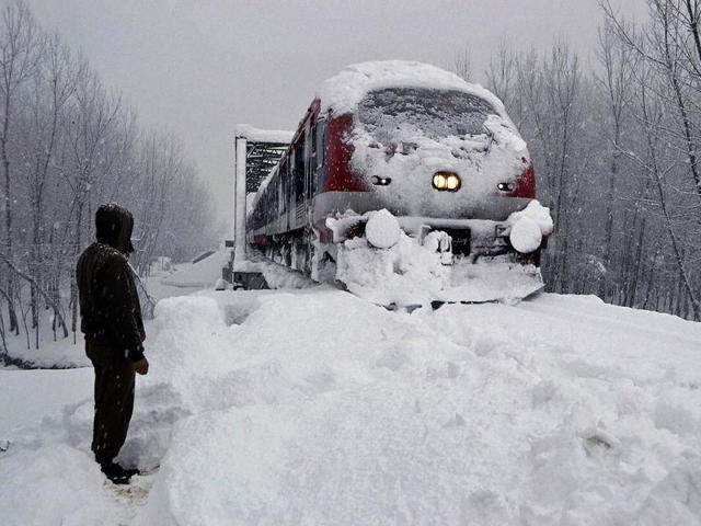 A railway policeman stands guard as a train runs on its tracks amid heavy snowfall in Kashmir’s Anantnag district. Most places in J&K recorded sub-zero temperatures. PTI Photo