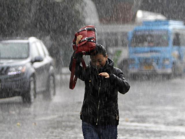 A woman walks through a street as it rains in Jammu. Heavy snowfall threw normal life out of gear in Jammu and Kashmir Wednesday, snapping road and air links between the state and the rest of the country. (AP Photo/Channi Anand)