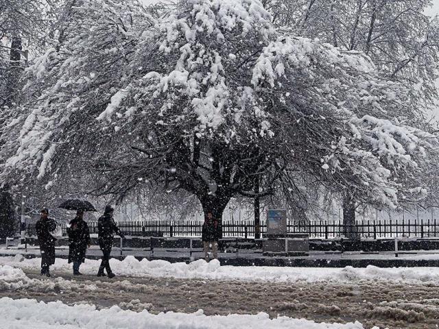 People walk during heavy snowfall in Srinagar. Kashmir valley experienced fresh snowfall prompting authorities to suspend traffic on Srinagar-Jammu national highway and air service. (PTI Photo)