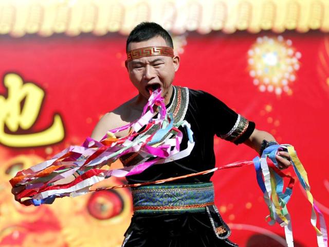 A man pulls ribbons from his mouth as he performs a feat of his strength during the opening of the temple fair for Chinese New Year celebrations at Ditan Park, also known as the Temple of Earth, in Beijing. A man pulls ribbons from his mouth as he performs a feat of his strength during the opening of the temple fair for Chinese New Year celebrations at Ditan Park, also known as the Temple of Earth, in Beijing.
