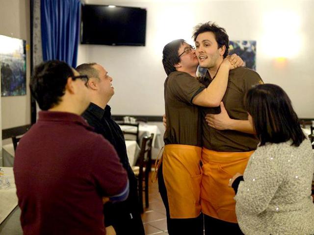 Simone Ippoliti (C-left), a young man with Down syndrome, kisses his chief (R) in the restaurant 'Locanda dei Sunflowers' where he works in Rome. (AFP photo)