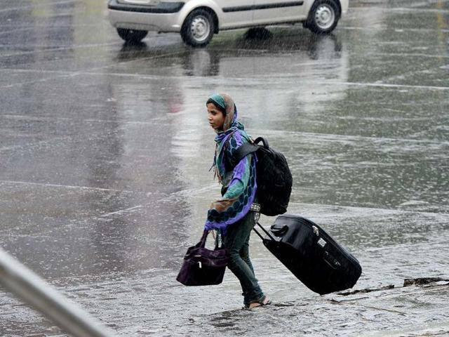 A woman drags her bag accross the street during unexpected rains in Mumbai (Kunal Patil/HT)