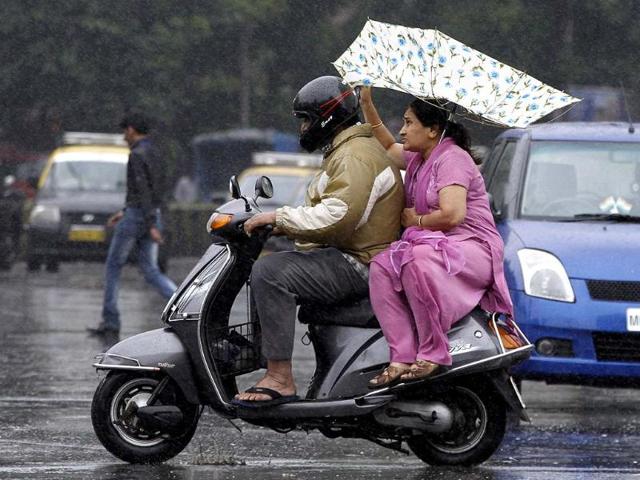 Sudden rainfall in Mumbai caught may unaware, including this couple on a scooter (Kunal Patil/HT)