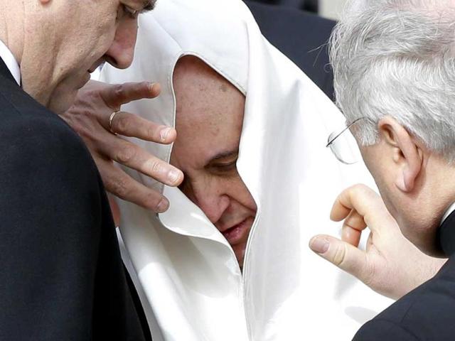 Pope Francis is helped with his mantle after it was moved by a gust of wind during the general audience in Saint Peter's Square at the Vatican.(Reuters photo)