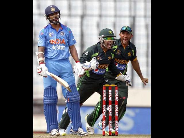 Shikhar Dhawan (L) reacts as Pakistan's wicketkeeper Umar Akmal (C) and Sohaib Maqsood celebrate his dismissal during their Asia Cup 2014 match in Mirpur. (Reuters Photo) 
