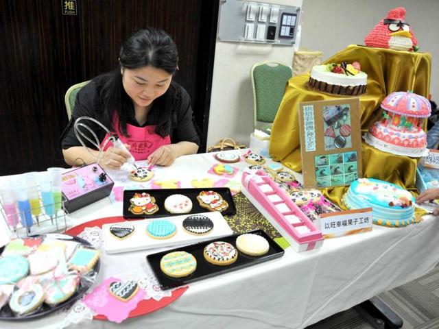 A cake maker uses a machine to draw a panda shape frosting on a cookies during a pre-show press conference for the Taipei International Bakery Show in Taipei. (AFP)