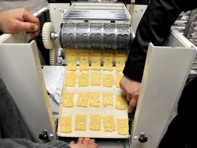 Two bakers make a cracker forming machine adjustment during the Taipei International Bakery Show, where thousands of bakery booths from many countries will be displayed. (AFP)