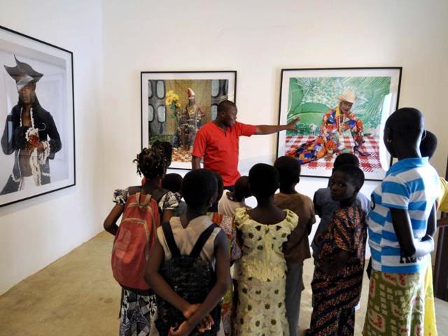 Cameroonian-and-Nigerian-artist-Samuel-Fosso-shows-children-through-an-exhibition-presenting-a-series-of-his-auto-portrait-photos-at-the-renovated-villa-Ajavon-AFP-photo Cameroonian-and-Nigerian-artist-Samuel-Fosso-shows-children-through-an-exhibition-presenting-a-series-of-his-auto-portrait-photos-at-the-renovated-villa-Ajavon-AFP-photo