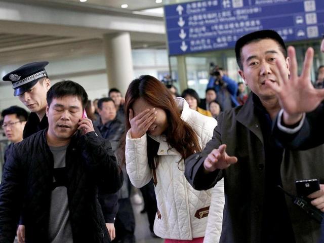 A woman (C), believed to be the relative of a passenger onboard Malaysia Airlines flight MH370, covers her face as she cries at the Beijing Capital International Airport in Beijing. (Reuters)