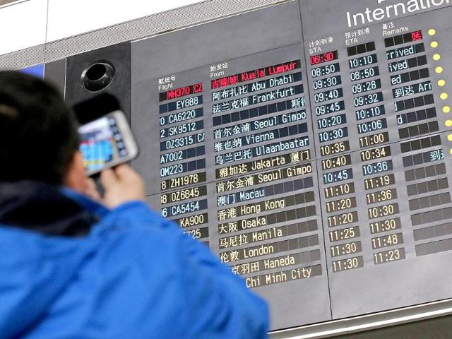 A man takes pictures of a flight information board displaying the Scheduled Time of Arrival (STA) of Malaysia Airlines flight MH370 (top, in red) at the Beijing Capital International Airport in Beijing (Reuters)