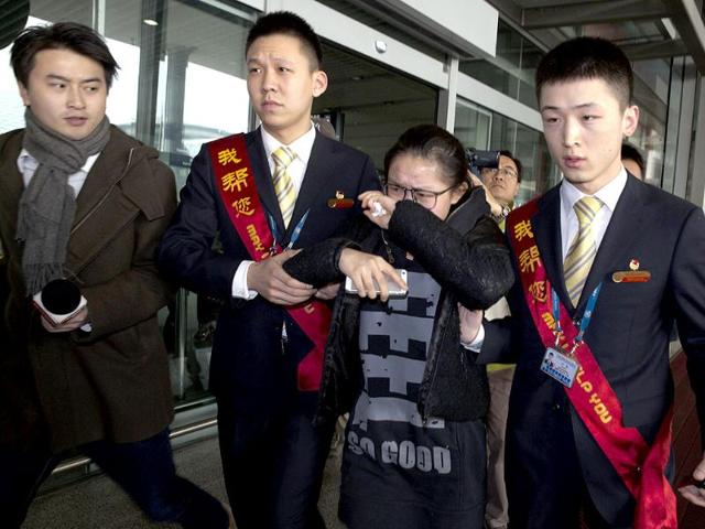 A woman in tears is helped by airport workers to a bus waiting for relatives of the missing Malaysian airliner at the international airport in Beijing, China. (AP Photo)