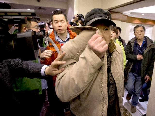 A man covers his face on his arrival at a hotel which is prepared for relatives or friends of passengers aboard a missing airplane, in Beijing. (AP Photo)