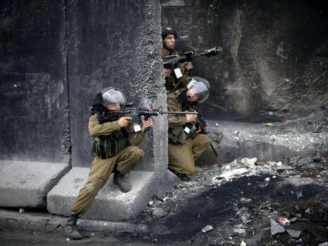 Israeli soldiers take positions during clashes following a march to commemorate International Women's Day at Qalandia checkpoint between Jerusalem and the West Bank city of Ramallah. (AP photo)