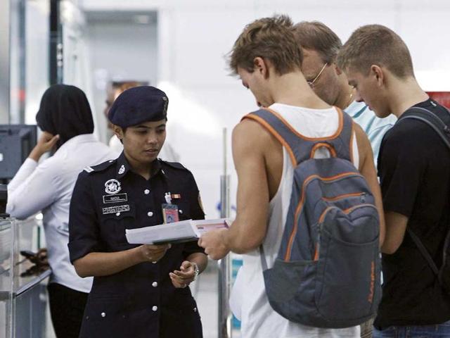 A customs officer checks the travel documents and passports of passengers at Kuala Lumpur International Airport in Sepang. (Reuters)