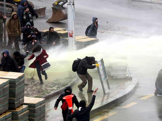 People run away as anti-riot olice fires water cannon to disperse thousands of people demonstrating following the death of Berkin Elvan, a teenage boy wounded in mass anti-government demonstrations last year, on March 11, 2014 near the Middle East Technical University (ODTU) in Ankara. (AFP Photo)