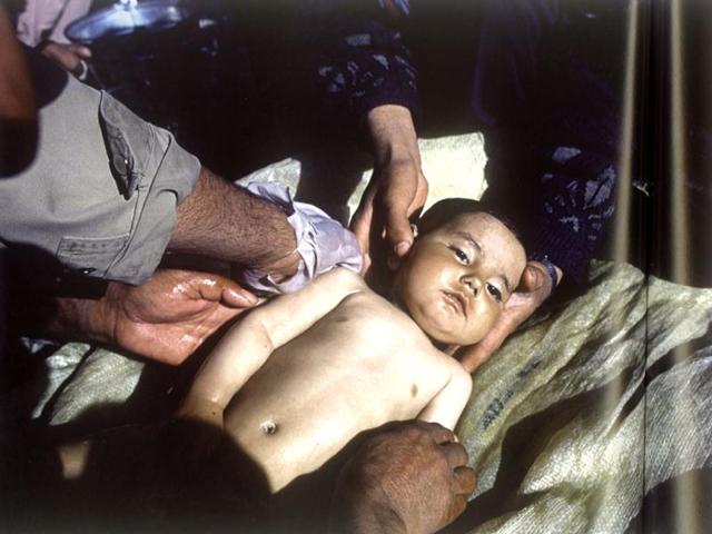 February 2001: Afghan men wash the body of a one-year-old-boy before burial. He died from exposure and influenza after sleeping outdoors. (Robert Nickelsberg)
