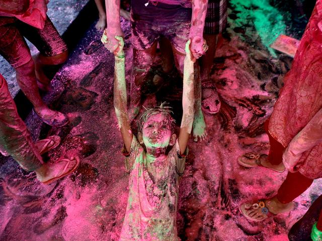 A boy drags another on the floor of an apartment as they play with colors during the Holi festival in Chennai. (AP Photo/Arun Sankar K)
