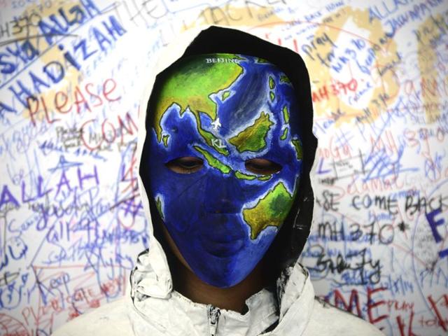 An unidentified woman wearing a mask depicting the flight of the missing Malaysia Airline, MH370, poses in front of the "wall of hope" at Kuala Lumpur International Airport in Sepang, Malaysia. (AP Photo)