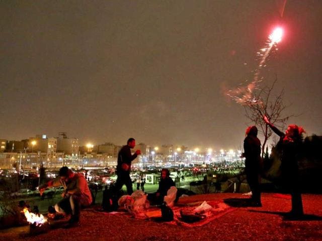 An Iranian woman lights fireworks during a celebration, known as “Chaharshanbe Souri,” or Wednesday Feast, marking the eve of the last Wednesday of the solar Persian year, in Pardisan park, Tehran, Iran. (AP Photo)