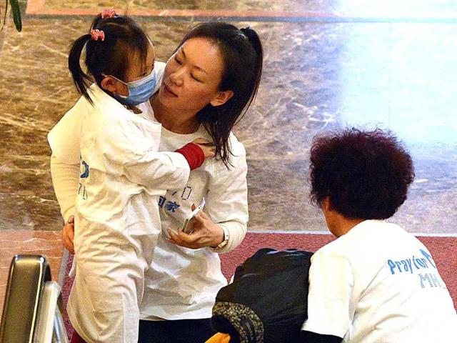 A Chinese woman who is a relative of a passenger from the missing Malaysia Airlines flight MH370, with her three-year-old daughter and another family member as they arrive at Metro Park Lido Hotel in Beijing. AFP