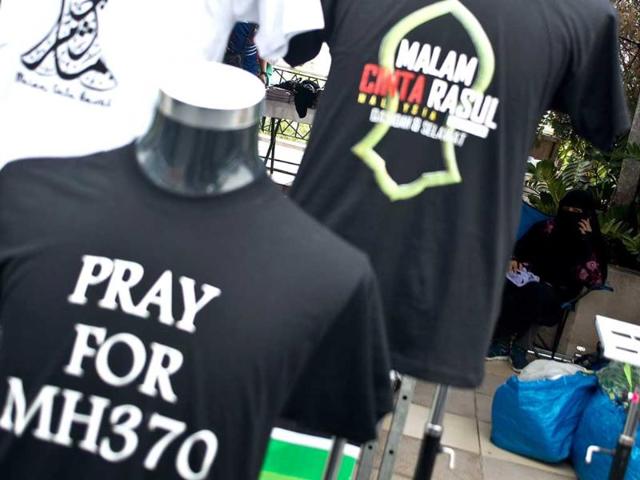 A veiled Muslim woman (R) waits at a stall selling t-shirts in memory of the missing Malaysia Airlines (MAS) MH370 flight outside the Putra mosque in Putrajaya. AFP