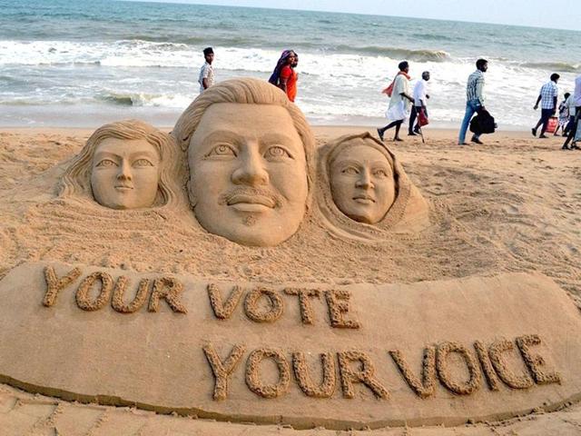 Sand artist Sudarsan Pattnaik creates a sand sculpture to aware voters with a message "Your Vote Your Voice" at Puri beach. (PTI photo)