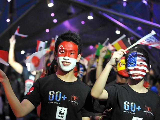 Volunteers wave flags to commemerate Earth Hour in Singapore. (AFP photo)