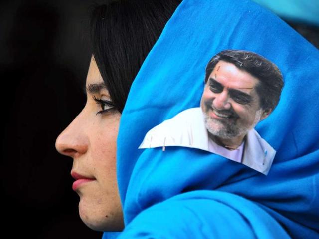 An Afghan woman with a portrait of presidential candidate Abdullah Abdullah on her scarf listens to his speech during a campaign rally in Herat. (AFP Photo) 