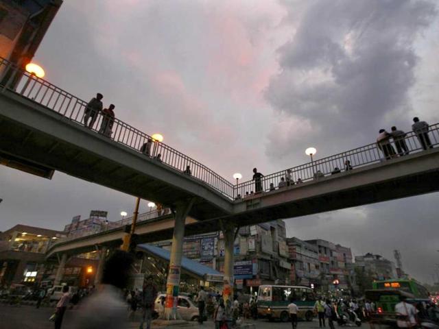 Daily commuters walking under dark clouds at Laxmi Nagar in New Delhi. (Raj K Raj/HT Photo)