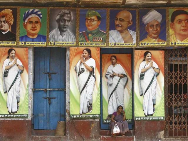 A woman speaks on a mobile phone as she sits under a building decorated with pictures of Mamata Banerjee, chief minister of West Bengal ahead of the general election in Kolkata. (Reuters)