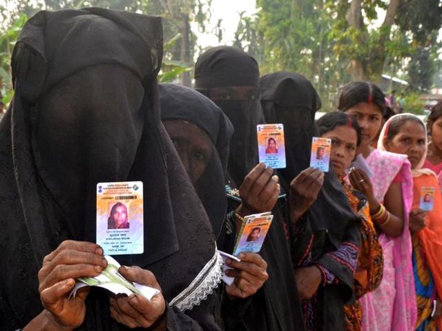 Voters pose with identification as they wait in line to vote outside a polling station in Koliabor, Assam. (AFP photo)
