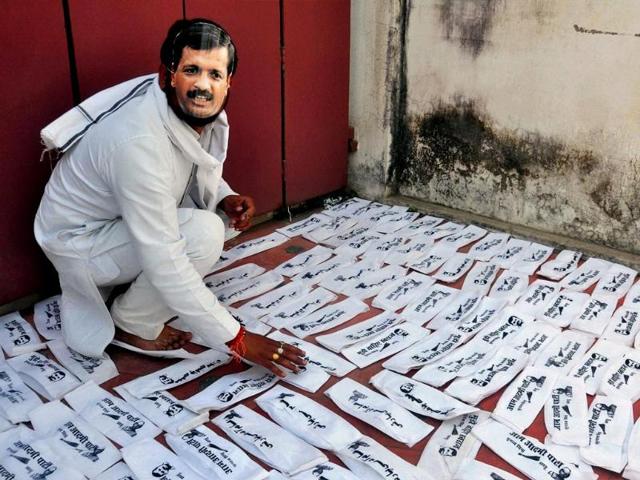 AAP worker with party leader Arvind Kejriwal mask arrange party's cap ahead of Lok Sabha election in Allahabad. (PTI Photo)