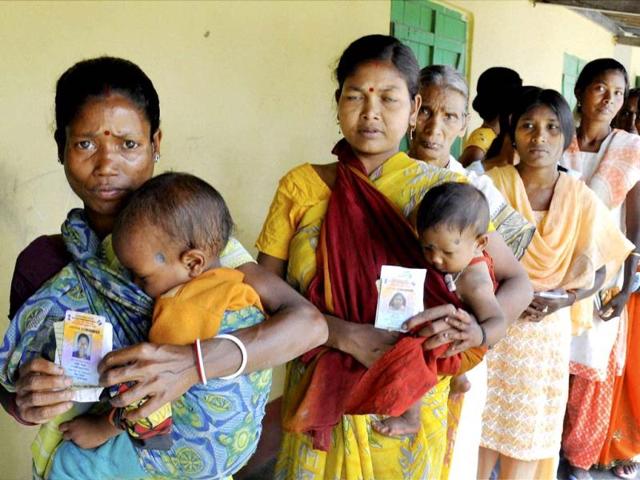People show their voter identity card as they queue to cast their vote at a polling booth at Dhekiajuli under Sonitpur district in Guwahati. (PTI Photo)