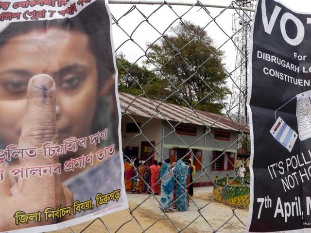Vote awareness placards are seen on a fence as voters wait in line outside a polling station in Dibrugarh. (AFP photo)
