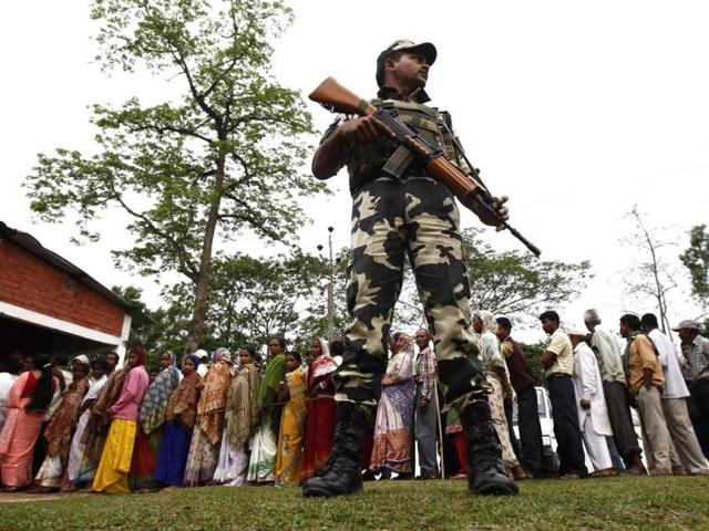 A security personnel stands guard as people line up to cast their vote outside a polling station in Nakhrai village in Tinsukia district in Assam. The country's 814 million eligible voters will vote in stages over the next five weeks. (Reuters photo)