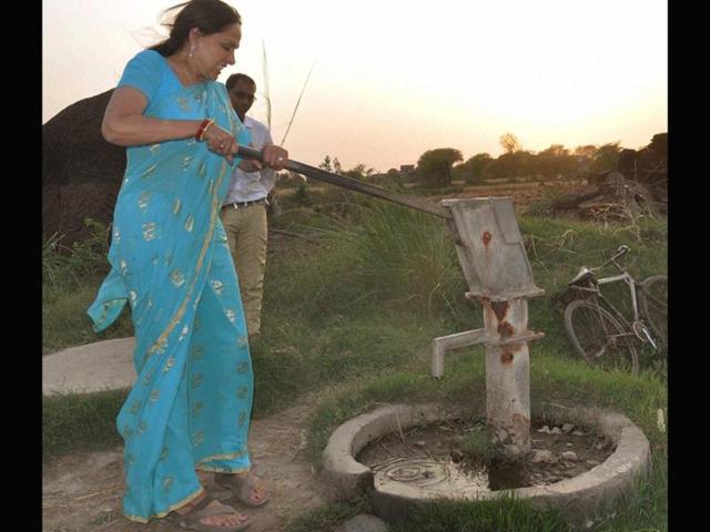 Bollywood actress and BJP candidate Hema Malini operates a hand pump at a village during her election campaign in Mathura. (PTI Photo)