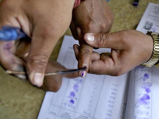 A polling officer applies ink on the finger of a voter at a polling station on the outskirts of Jammu. (Reuters Photo)