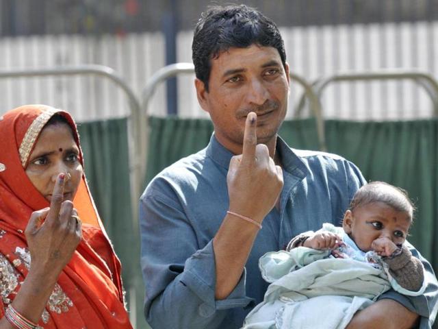 A couple poses along with their child after casting their vote at a polling booth in New Delhi. (Sonu Mehta/HT Photo)
