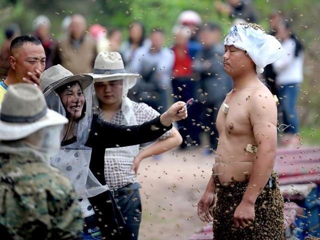 This picture shows people watching She Ping covered with a swarm of bees on a small hill in southwest China's Chongqing (AFP Photo)