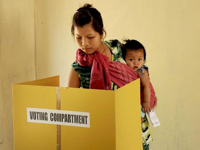 A voter holds a child as she casts her ballot at a polling station at Bungthuam, on the outskirts of Aizwal, in Mizoram. (AFP photo)