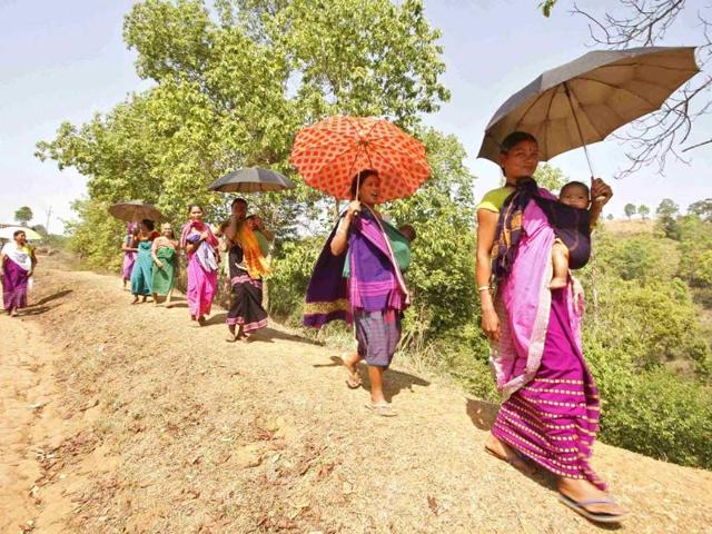 Women carrying their children walk back to their homes after casting their vote during Lok Sabha elections at a polling station at Putsari village, in Assam. (Reuters photo)